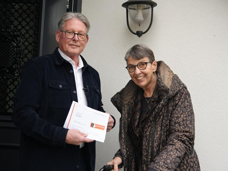 Jouke Wijnstra met brief in de hand, staat met Jetta Klijnsma bij de voordeur.