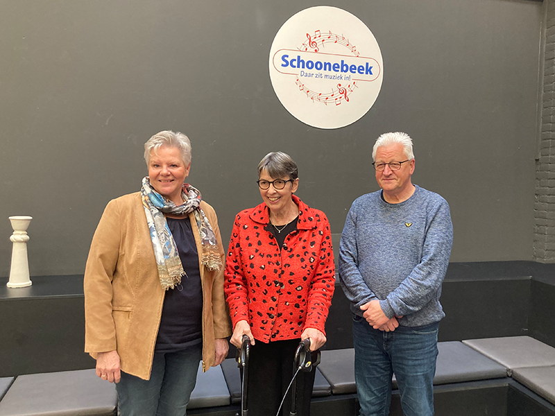 Jetta Klijnsma staat tussen een man en vrouw met op de achtergrond afbeelding met Schoonebeek daar zit muziek in