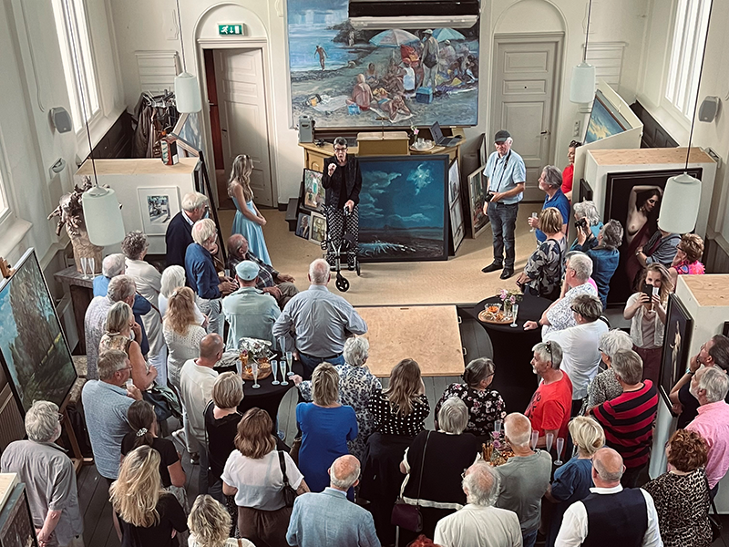 Jetta Klijnsma staat tussen een man en vrouw met op de achtergrond afbeelding met Schoonebeek daar zit muziek in