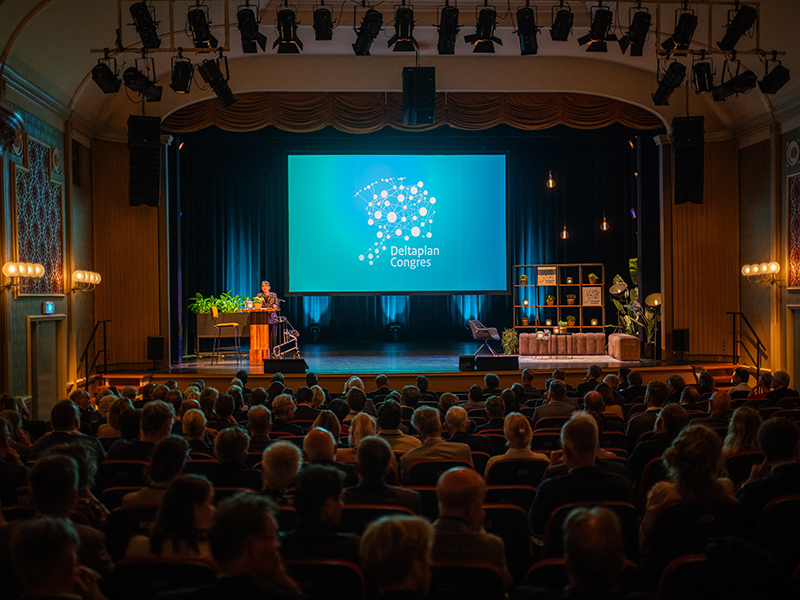 Leonie Visser en Jetta Klijnsma zitten achter een tafel en voor de kansel met elk een microfoon in de hand.